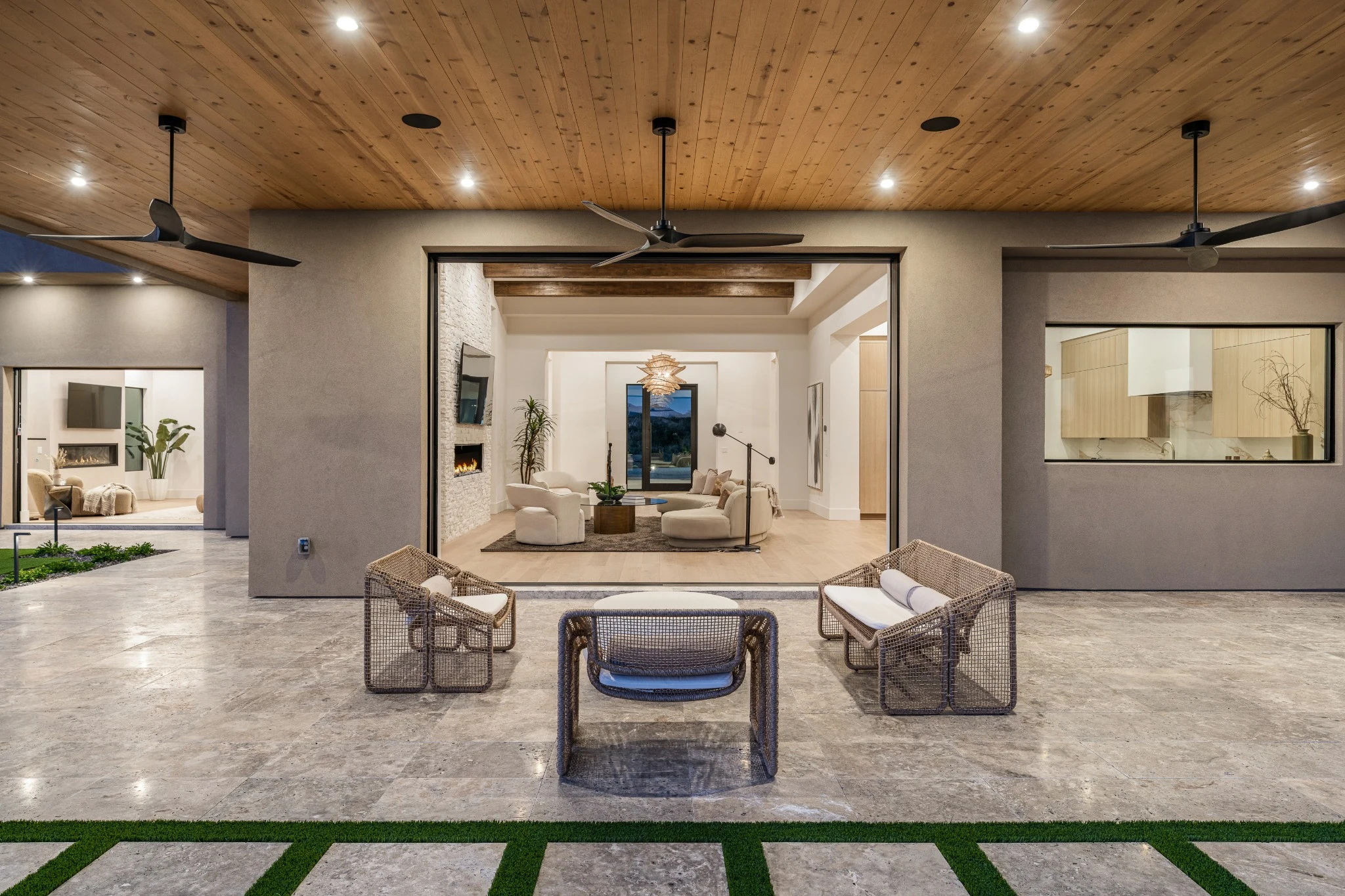 Covered courtyard with a timber ceiling, woven seating, and a view into the home